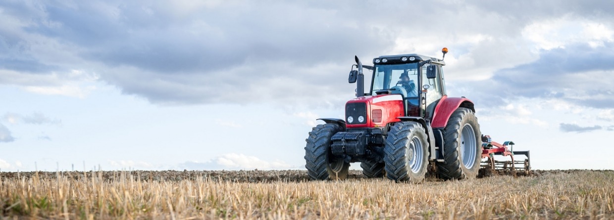 Rode tractor dat op het land aan het werk is